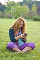 Fototapeta premium woman talking on phone top of the grass