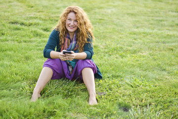 Fototapeta premium woman talking on phone top of the grass