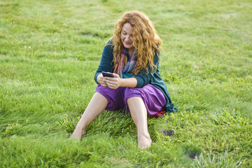 Fototapeta premium woman talking on phone top of the grass