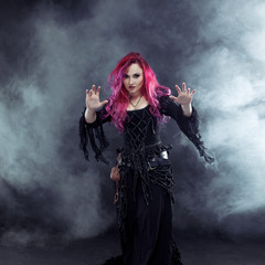 Obraz premium Halloween Witch creates magic. Attractive woman with red hair in witches costume