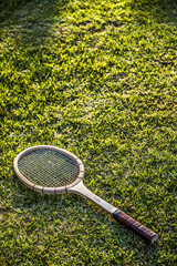 Vintage wood tennis racket on green grass garden
