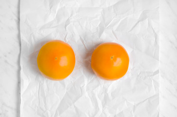 Two yellow tomatoes on a white parchment