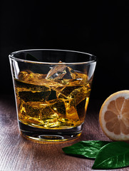 Glass of whiskey with ice on a wooden table