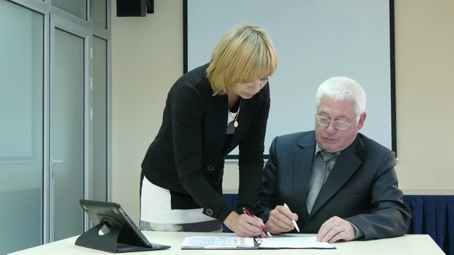  businessman and businesswoman signing documents