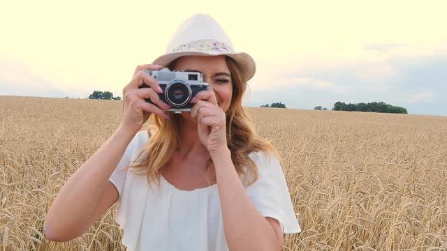 Woman taking photos with retro film camera on the field
