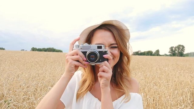 Woman taking photos with retro film camera on the field