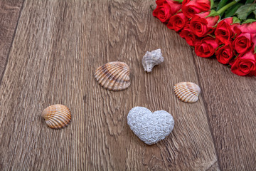White heart, roses and shells on a wooden background
