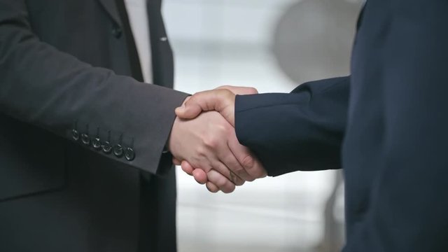 Closeup of two business partners standing and shaking hands