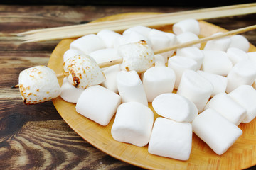 Fluffy white marshmallow in wooden bowl on old wooden table