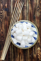 Fluffy white marshmallow in wooden bowl on old wooden table