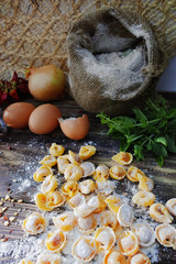 Homemade pasta ravioli on old wooden table with flour, eggs, kit