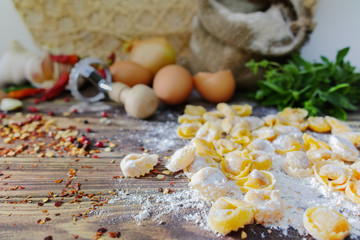 Homemade pasta ravioli on old wooden table with flour, eggs, kit