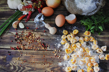 Homemade pasta ravioli on old wooden table with flour, eggs, kit