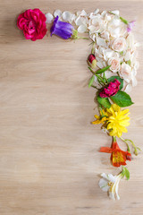 One angle frame made of different flowers on wooden background.