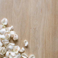 Fototapeta na wymiar White rose petals on wooden background with space for your text.