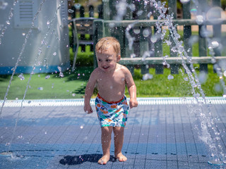 Boy running under the water sprinklers