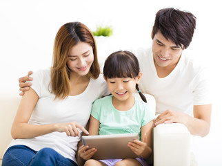 Fototapeta na wymiar happy family and daughter using tablet on sofa
