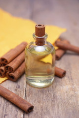 Obraz na płótnie Canvas Essential aroma cinnamon oil in a glass bottle with cinnamon sticks on wooden background.