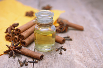 Essential aroma cinnamon oil in a glass bottle with cinnamon sticks on wooden background.