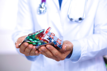 A young doctor holds the patient's hand with pills