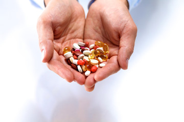 Fototapeta premium A young doctor holds the patient's hand with pills