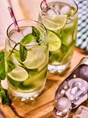 Alcohol drink. On wooden boards three glasses with alcohol drink and ice cubes. Drink number hundred fifty nine cocktail mohito and scoop ice with straw. Country mohito cocktail. Light background.