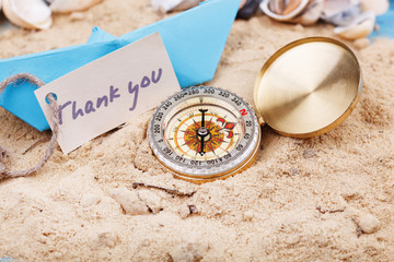 Fototapeta na wymiar compass in the sand with sign - Thank you