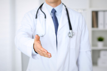 Male medicine doctor offering helping hand  for  handshake. Partnership and trust concept.