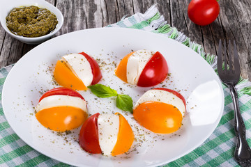 Caprese salad of tomatoes and mozzarella with sauce pesto, close