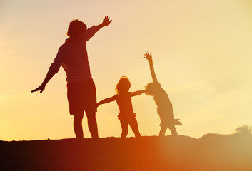 Fototapeta premium father with son and daughter silhouettes play at sunset