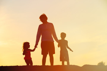 father with son and daughter walking at sunset
