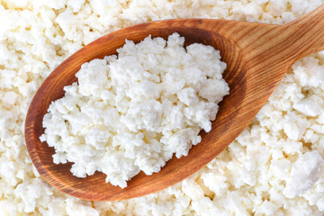 crumbly cottage cheese in the wooden spoon lying diagonally upwards - 115854510