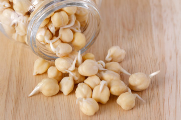 germinated chickpeas pour out of a glass jar on the wooden background - 115854935