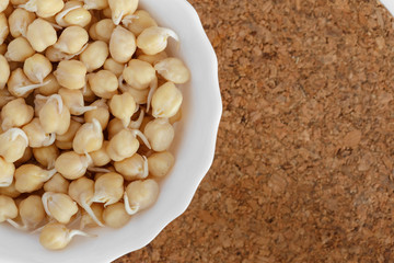 germinated chickpeas in a white bowl on the cork background - 115854946