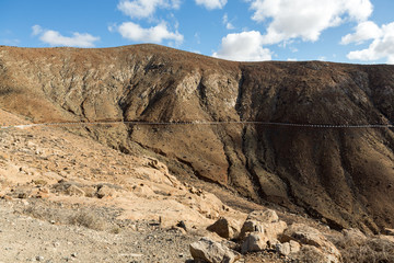 Fototapeta premium Beautiful volcanic mountains and the road on a mountain slope. Road from la Pared to Betancuria . Fuerteventura. Canary Islands