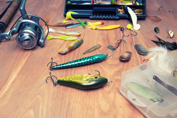 Fishing baits and rod isolated on wooden background