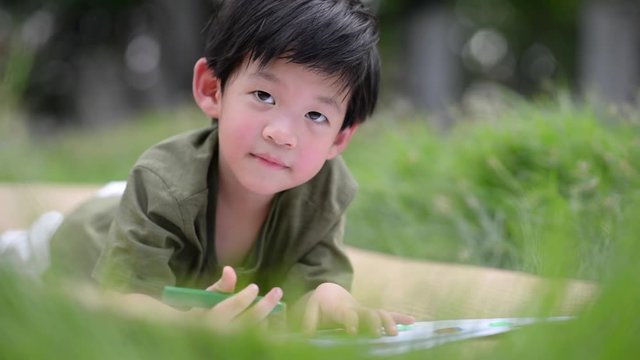 Cute Asian child drawing picture with crayon