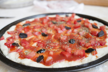 raw pizza with  tomato sauce and olives pizza