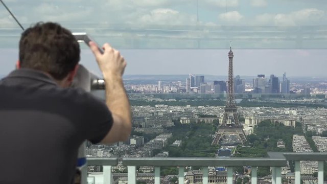 Man In Telescope Watches Panoramic View Of Paris. The Montparnasse Tower Panoramic Observation Deck has the most beautiful view of Paris