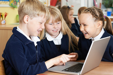 Group Of Elementary School Children Working Together In Computer