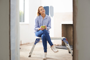 Woman Sitting In Property Being Renovated