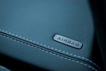 Luxury car interior details. Airbag badge on leather dashboard
