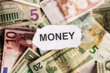 Focus on the word MONEY on piece of torn white paper with blur background