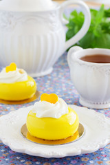 Cakes with mango and passion fruit with cream in the mirror glaze. Selective focus.