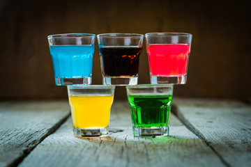 Selection of colorful shot drinks on white wood background