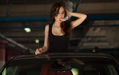 Obraz na płótnie Canvas Young beautiful woman smoking ( vaping ) e-cigarette with smoke in car luke