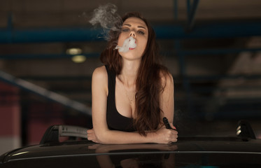 Fototapeta na wymiar Young beautiful woman smoking ( vaping ) e-cigarette with smoke in car luke