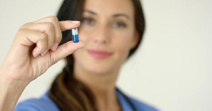 Doctor Or Nurse Holding Up A Capsule Between Her Finger And Thumb With A Smile  Focus To The Medication  With Copy Space