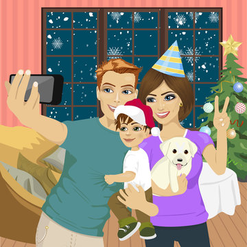 Smiling mother, father and little son making selfie with camera over living room and christmas tree background