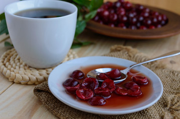Cherry jam and a cup of tea on a light wooden background. The top view